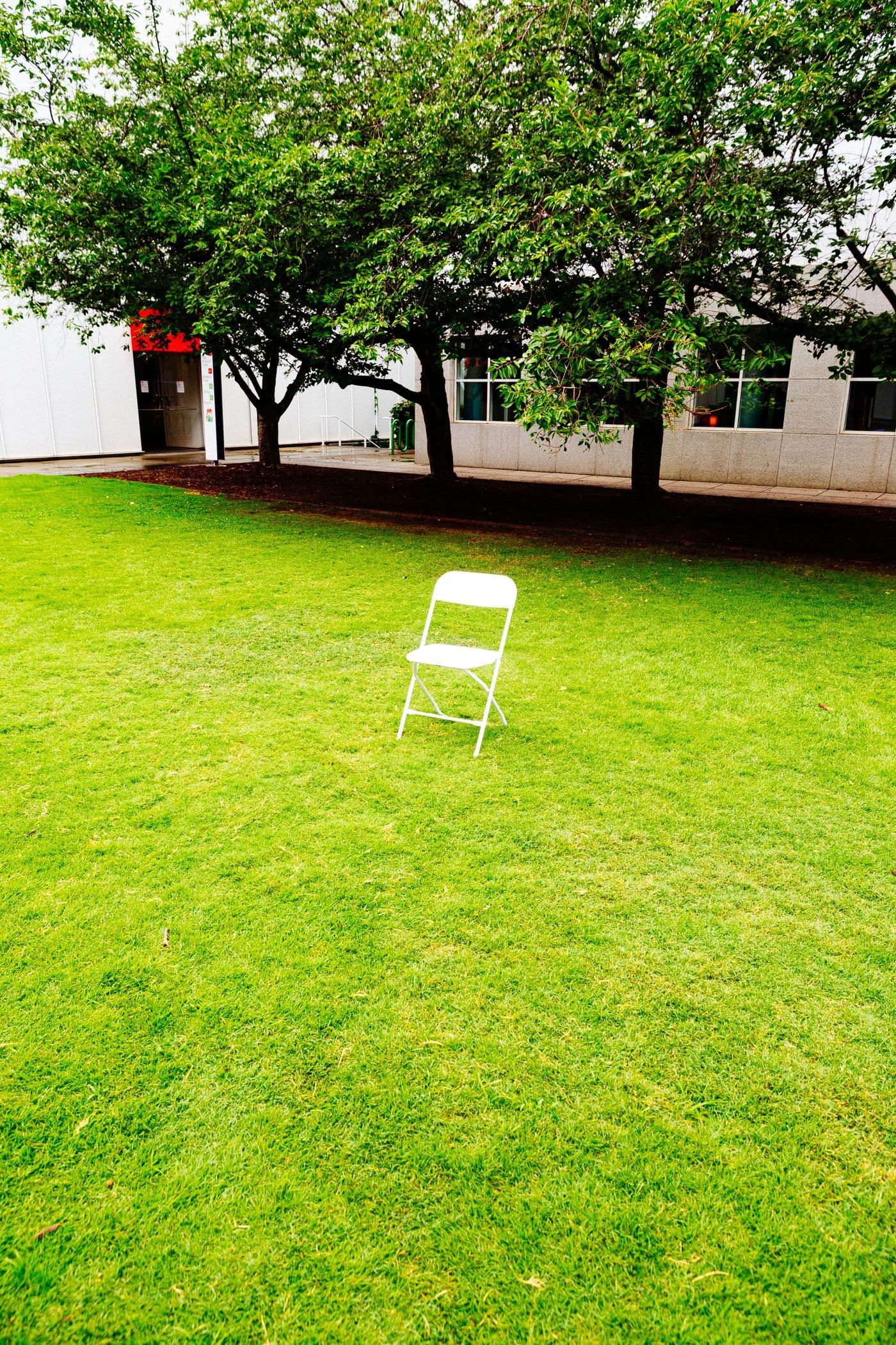 A white plastic folding chair set up on a lawn