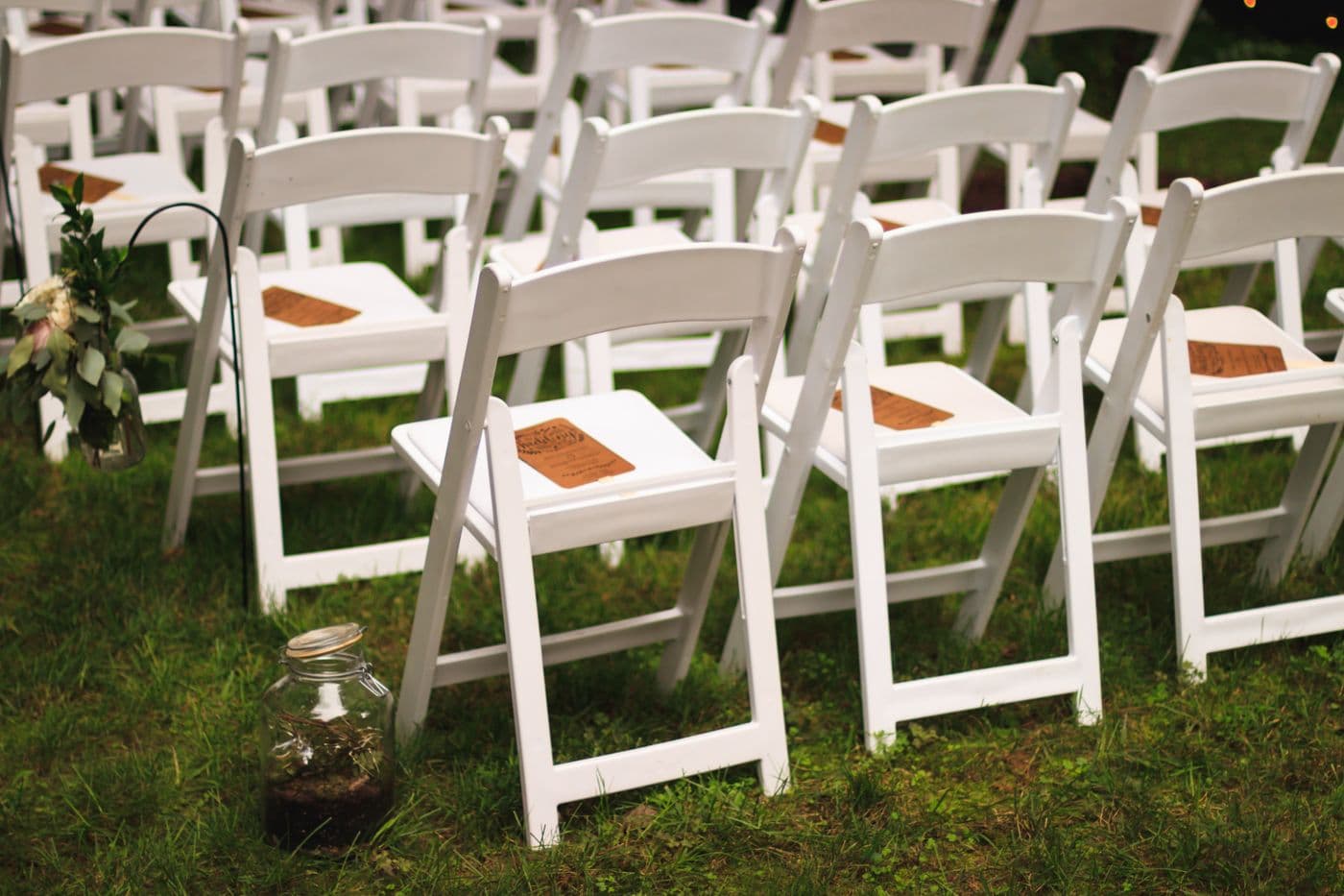 Rows of clean white folding chairs set up outdoors