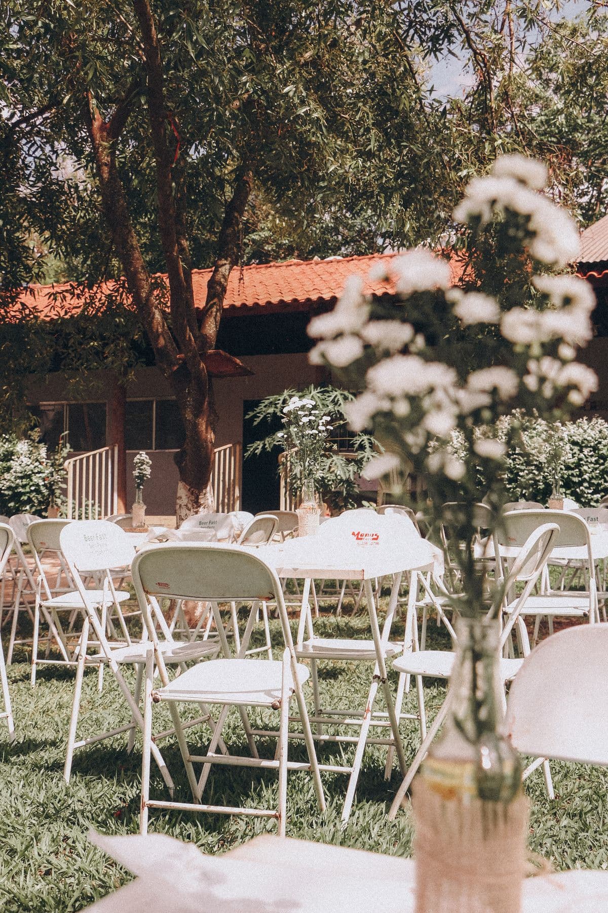 White foldable tables and white folding chairs set up in a garden