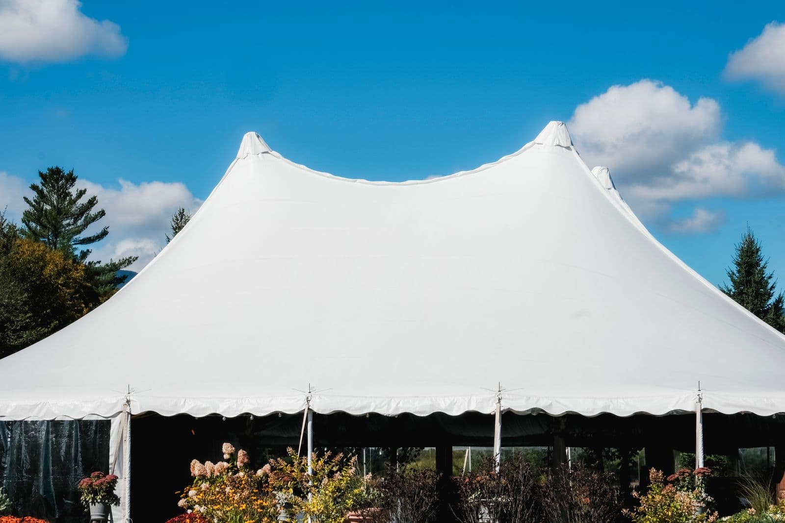 White peaked marquee tent set up outdoors against a blue sky