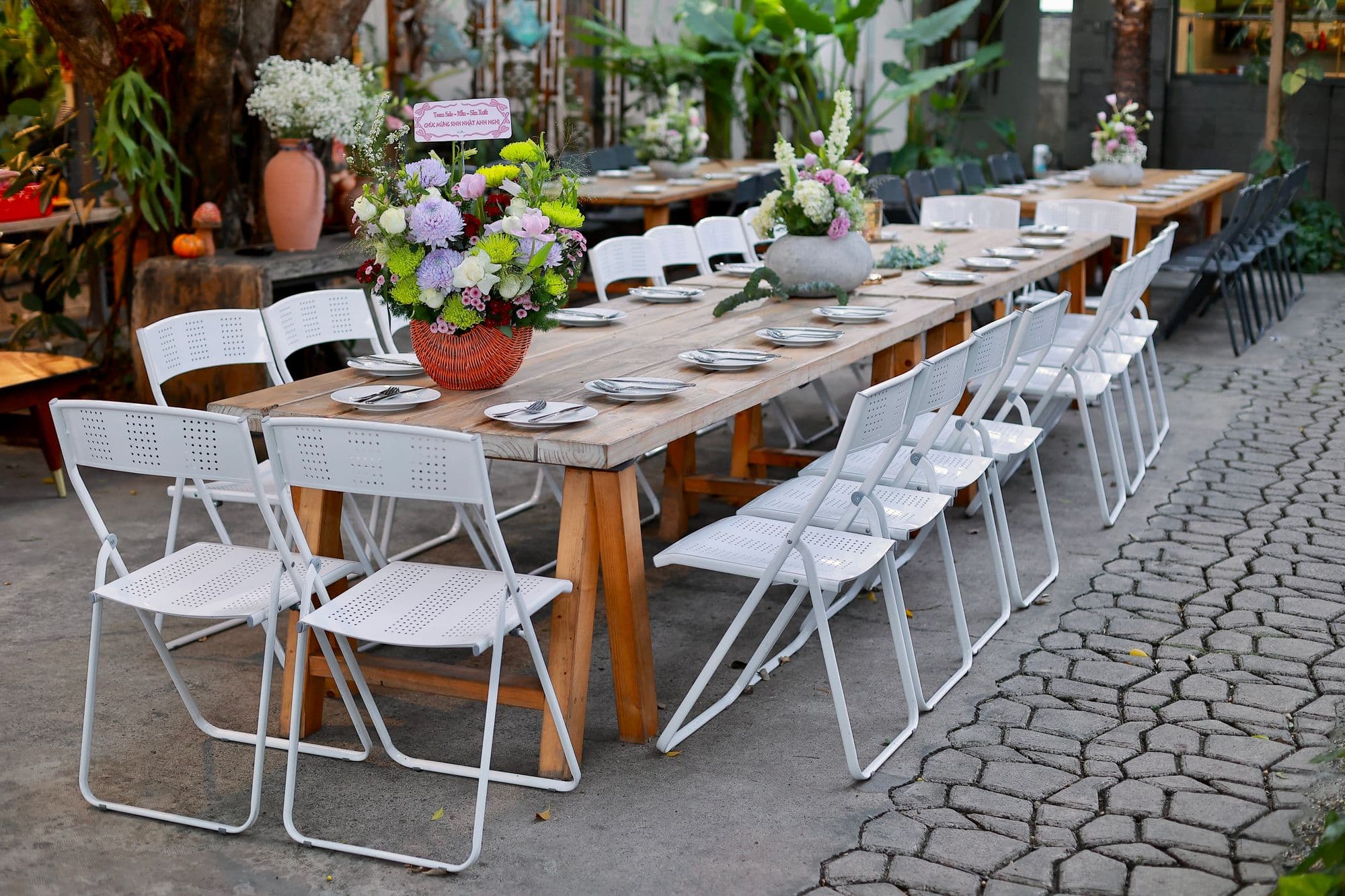 A long banquet table lined with white folding chairs set up outdoors